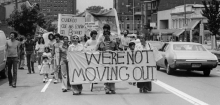 Black and white photo of people Protesting and Holding Signs saying "We're not moving out"