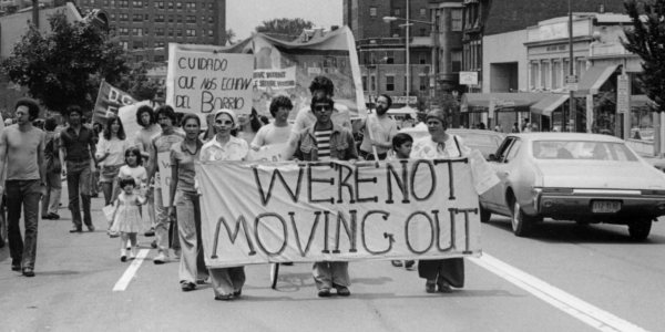 Black and white photo of people Protesting and Holding Signs saying "We're not moving out"