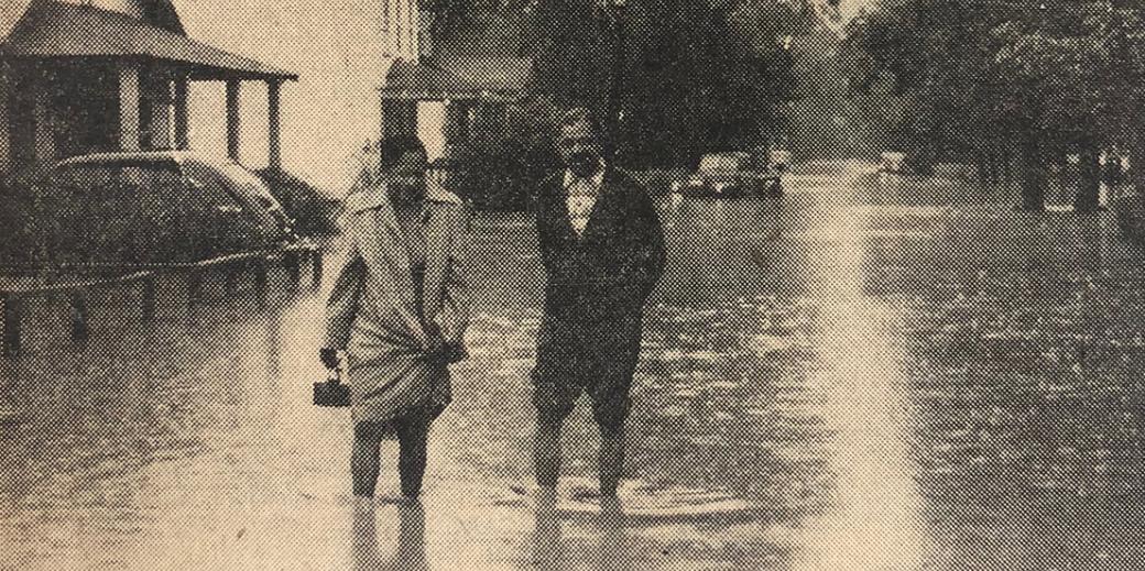 Print magazine image of a couple walking through flooded streets of North Brentwood, Md. in 1955.