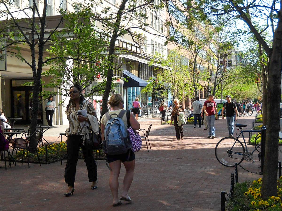 People walking in a pedestrian area in Washington DC with green trees. 
